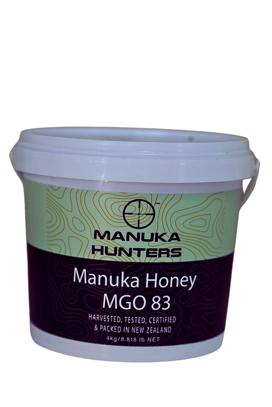 A plastic tub of Manuka Honey MGO 83 by Manuka Hunters, with a green and white label, placed against a plain background.