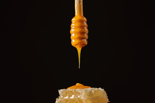 Manuka Honey - honey dripping from a honey spoon onto honeycomb