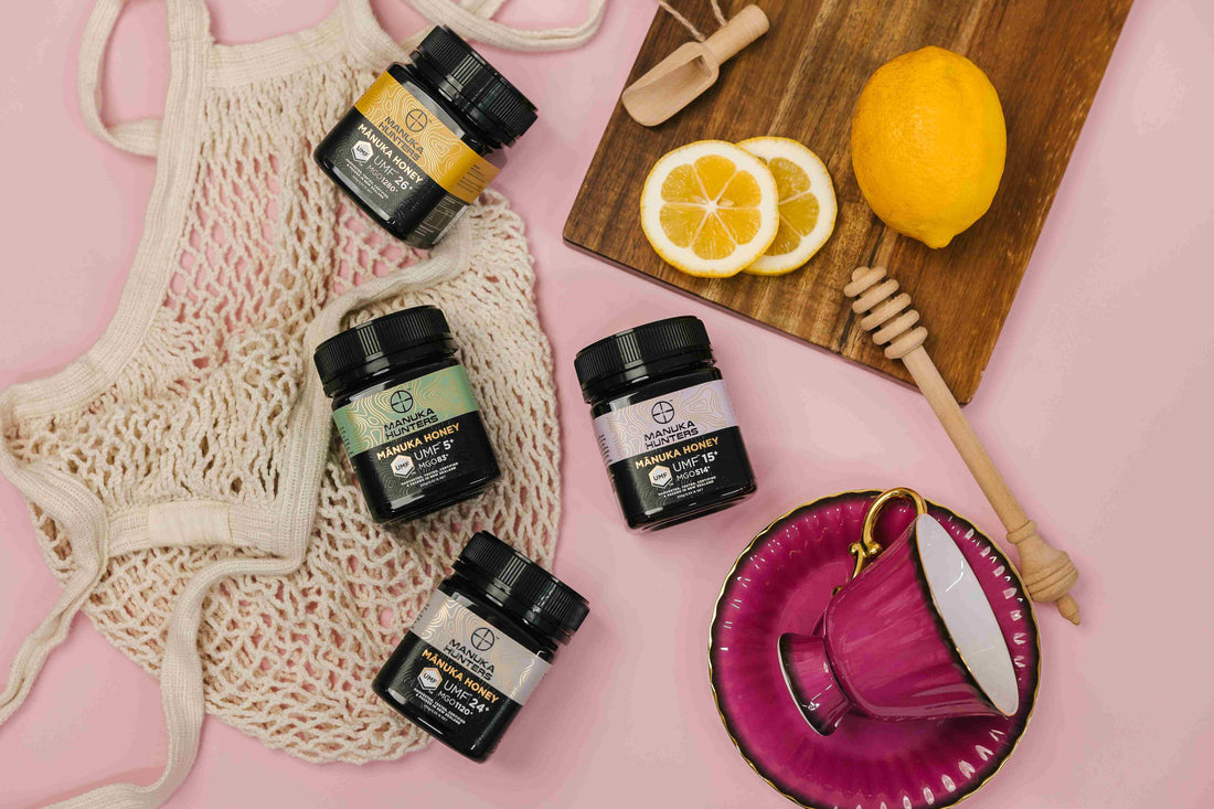 Manuka Hunters honey jars displayed with Lemons, a tea cup, a cutting board and a picnic bag.