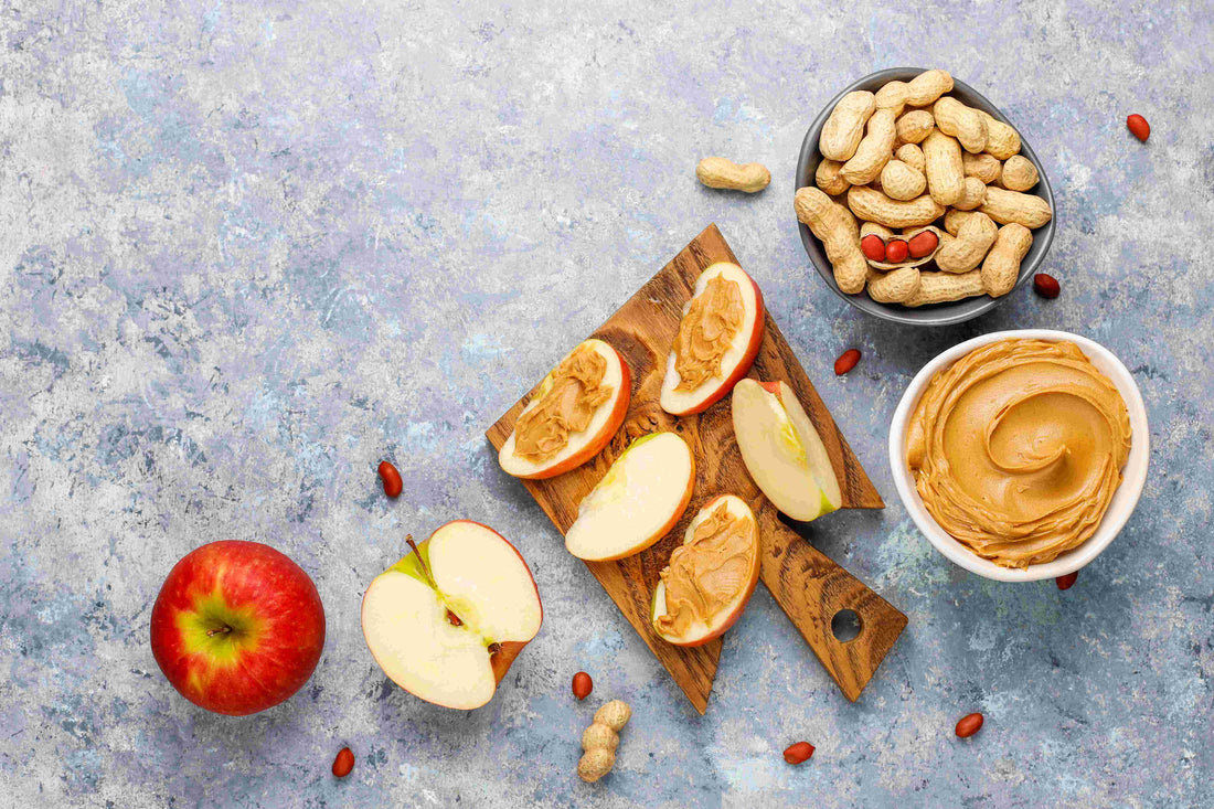 Apple slices topped with peanut butter on wooden board, Manuka Hunters snack recipe