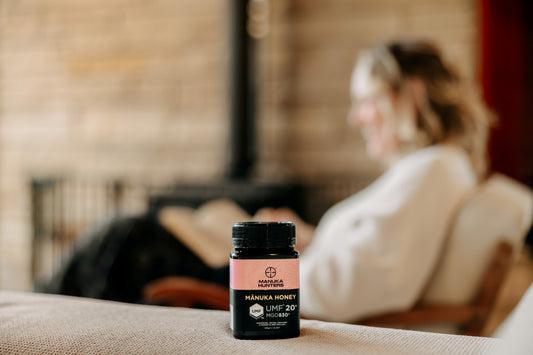 manuka hunters honey jar in the foreground. A woman relaxing with a book in the background