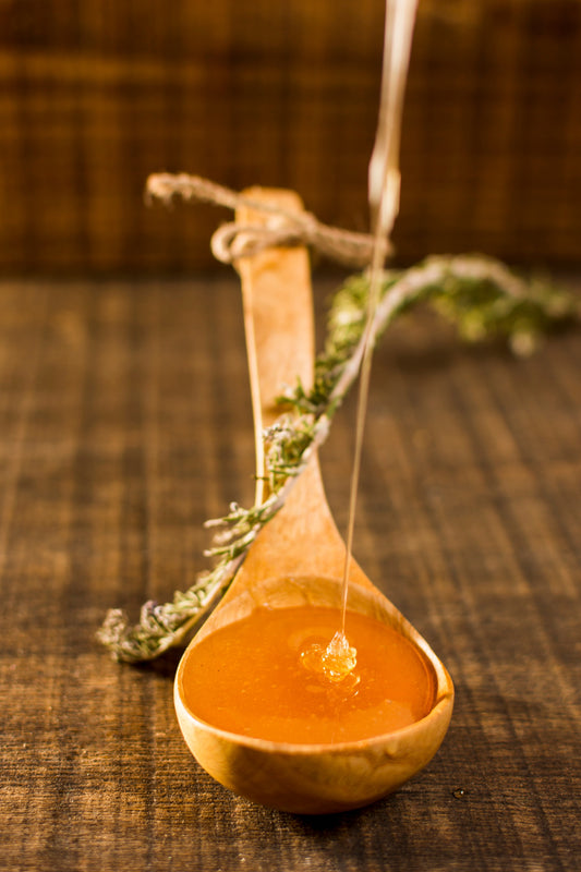wooden spoonful of flowing golden manuka honey